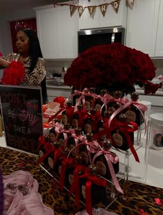 a woman standing in front of a table filled with red roses and chocolate covered candies