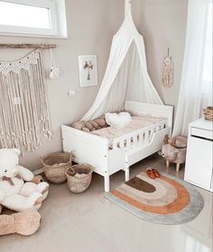 a baby's room with a white bed, teddy bears and other toys on the floor