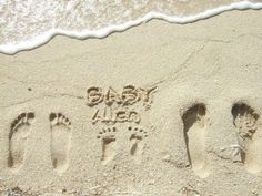 two people's footprints in the sand next to an ocean wave and their name written on it