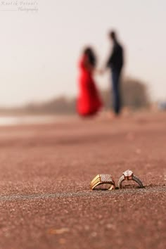 two people walking on the beach with rings in front of them