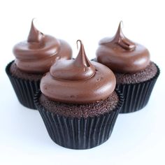 three cupcakes with chocolate frosting on top sitting next to each other in front of a white background