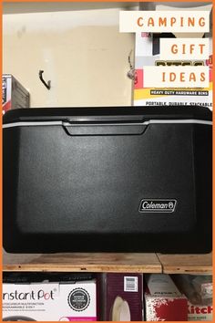 a black cooler sitting on top of a wooden shelf next to other boxes and books