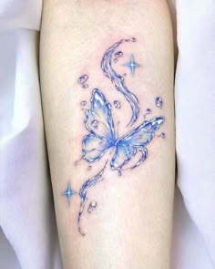 a blue butterfly tattoo on the right thigh with water droplets and stars around it's wings