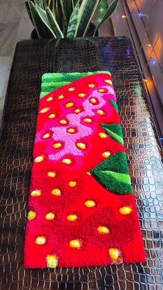 a red rug with yellow dots on it sitting on a table next to a potted plant