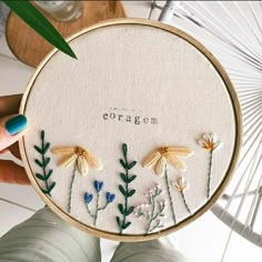 someone is holding up a cross - stitch embroidery kit with flowers and leaves on it