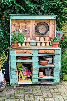 an old dresser with potted plants and pots on it's top is sitting in the garden