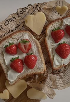 two pieces of bread with cream and strawberries on top, next to buttered crackers