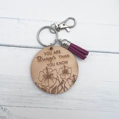 a wooden keychain with a tassel on it that says, you are stronger than you know