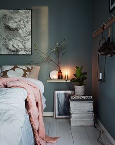 a bedroom with blue walls and white flooring is lit by two candles on the nightstands