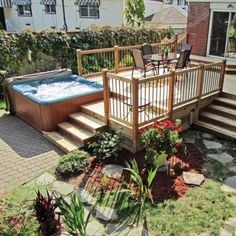 a hot tub sitting on top of a wooden deck next to a small garden area