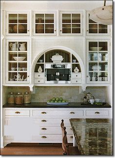 a kitchen with white cabinets and marble counter tops