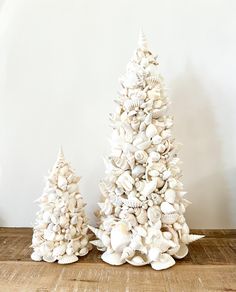 two white christmas trees with seashells on them