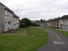 an empty street with houses on both sides and grass in the middle, along side