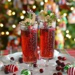 two glasses filled with red liquid sitting on top of a table next to christmas decorations