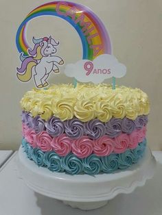 a birthday cake decorated with rainbow swirls and a unicorn topper