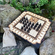 a wooden chess board sitting on top of rocks next to a drawstring bag