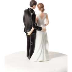 a bride and groom figurine standing next to each other on a white surface