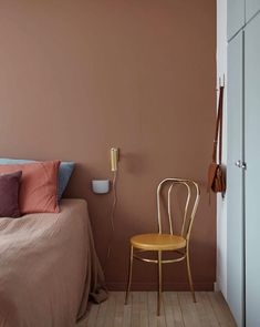 a bed room with a neatly made bed and a wooden chair next to the bed