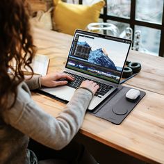 a woman sitting at a table with a laptop computer on her lap and mouse in front of her