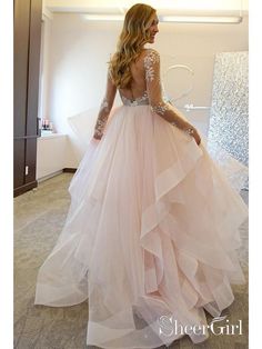 a woman in a pink wedding dress looking at something on the wall with her back to the camera