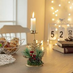 a candle is lit on a table next to some books and other decorations with lights in the background