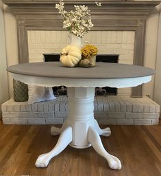 a white table with flowers on it in front of a fireplace