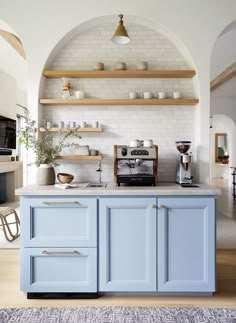 a kitchen with blue cabinets and shelves on the wall, and an instagramr above it