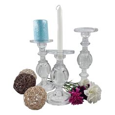 three glass candlesticks with flowers on the side and one candle in the middle