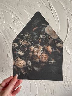 a hand holding up a piece of paper with flowers on it