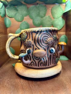 a ceramic coffee cup with an animal face on it's side sitting on a wooden table