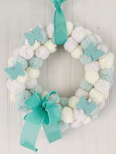 a white and blue wreath with pom - poms hanging on the front door