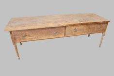 an old wooden table with two drawers on one side and three legs on the other