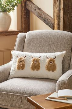 a chair with three pillows on it in front of a wooden table and window sill