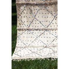 an old rug is laying on the grass in front of some green grass with blue and white beads