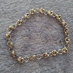 a close up of a gold chain bracelet on a gray surface with the clasp undone