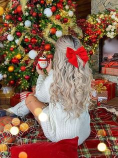 a woman sitting in front of a christmas tree