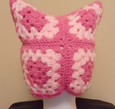 a pink and white knitted cat hat on top of a mannequin head