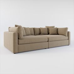 a beige couch with many pillows on the top and bottom corner, sitting in front of a white wall