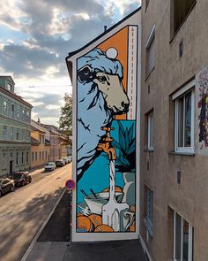 a mural on the side of a building in an urban area with cars parked nearby