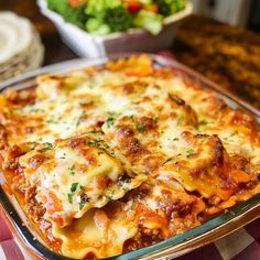 a casserole dish with meat, cheese and vegetables in it on a table