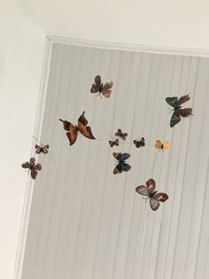 there are many butterflies flying in the air on this white wall and some wires attached to the ceiling