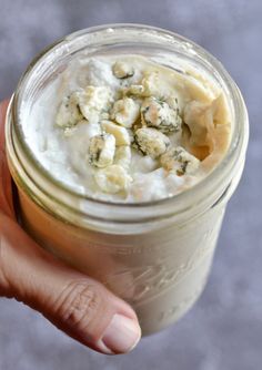 a hand holding a mason jar filled with food