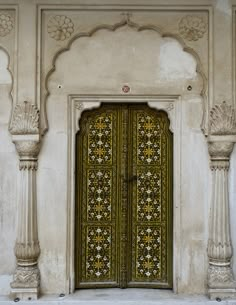 an ornately decorated door to a building with columns and arches on the outside wall