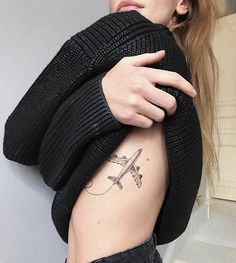 a woman with a small airplane tattoo on her left side ribcage and arm