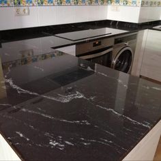 a kitchen with black marble counter tops and white cabinets, along with a washer and dryer