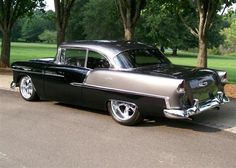 an old car is parked on the side of the road in front of some trees