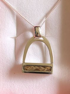 a gold necklace with a small metal object on it's chain, sitting on a pink background