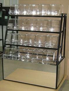 a display case filled with glasses on top of a wooden table next to a wall