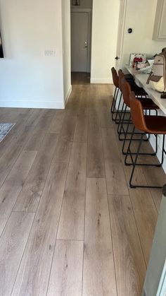 an empty kitchen and dining room with wood flooring on the walls, along with bar stools