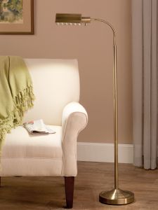 a living room with a white chair and a gold floor lamp next to a couch